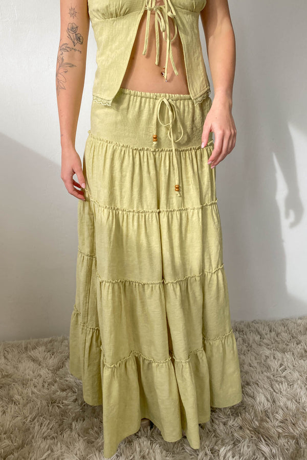 Person wearing a light green tiered dress on a neutral background